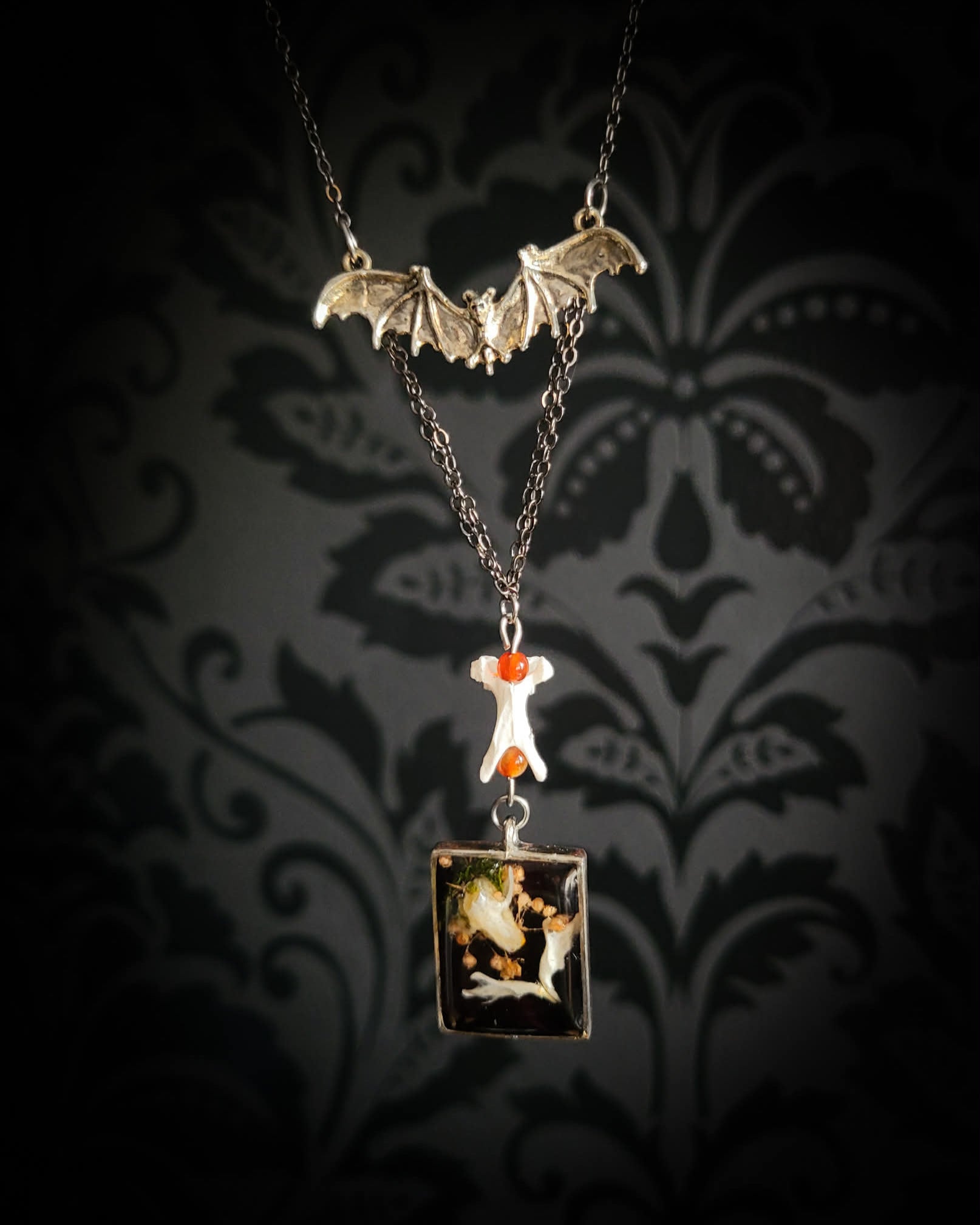 Handmade gothic necklace — mouse skull and jaw with dried flowers in hexagonal resin pendant, vertebrae connector, metal bat charm, carnelian beads