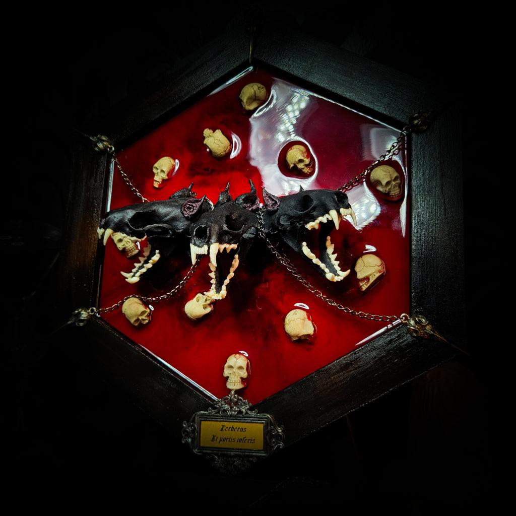 Cerberus | Collectors Work — handmade gothic wall decor with three real mink skulls, sculpted ears and tongues, decorative chains, silver crow ornaments and Latin inscription plaque on deep red velvet, hexagon frame, 23x27cm
