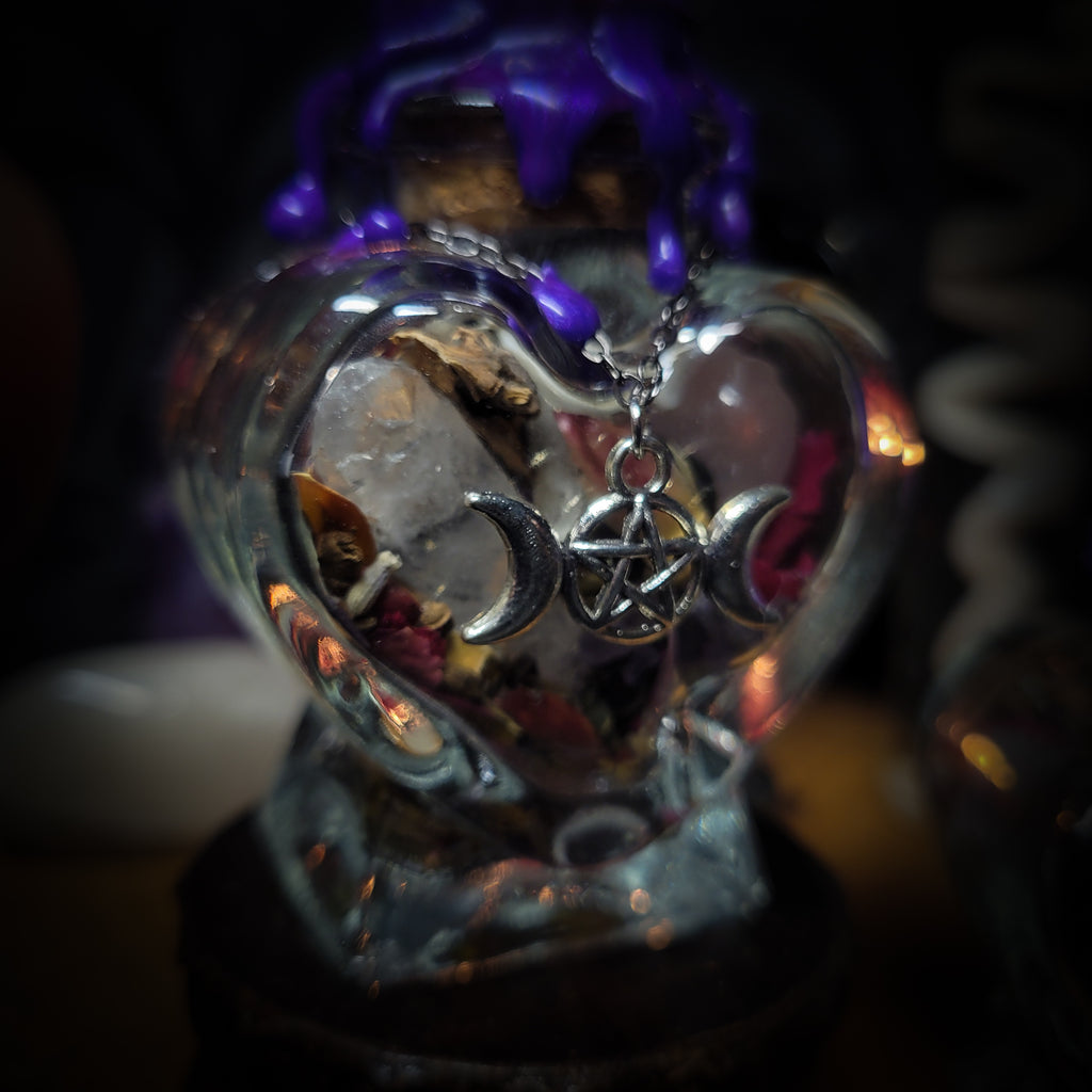 Handmade gothic twin spell jar set — two heart-shaped glass vessels sealed with violet wax and amethyst moon, filled with herbs, crystals and bones for love binding ritual