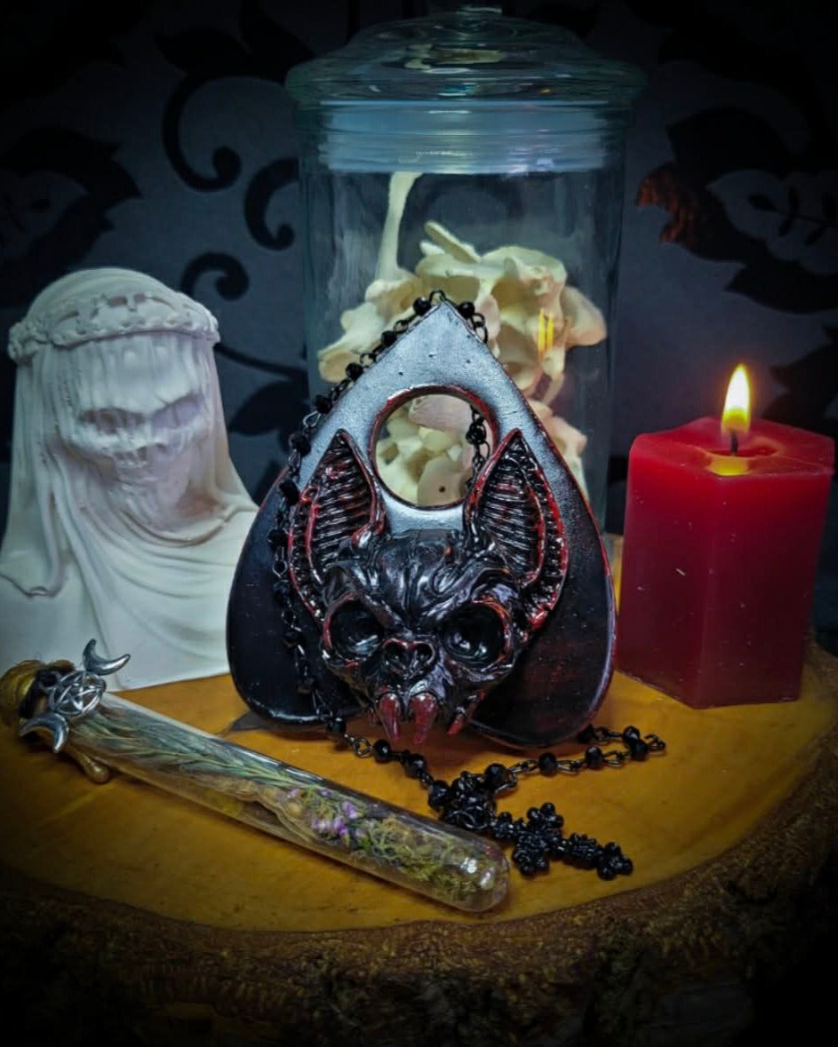 Ouija Planchette — handmade gothic planchette sculpture, made to order. Hand-cast bat and demonic face centerpiece in classic planchette shape, dark bloody finish with deep red accents. Occult altar decor, 8x9cm.
