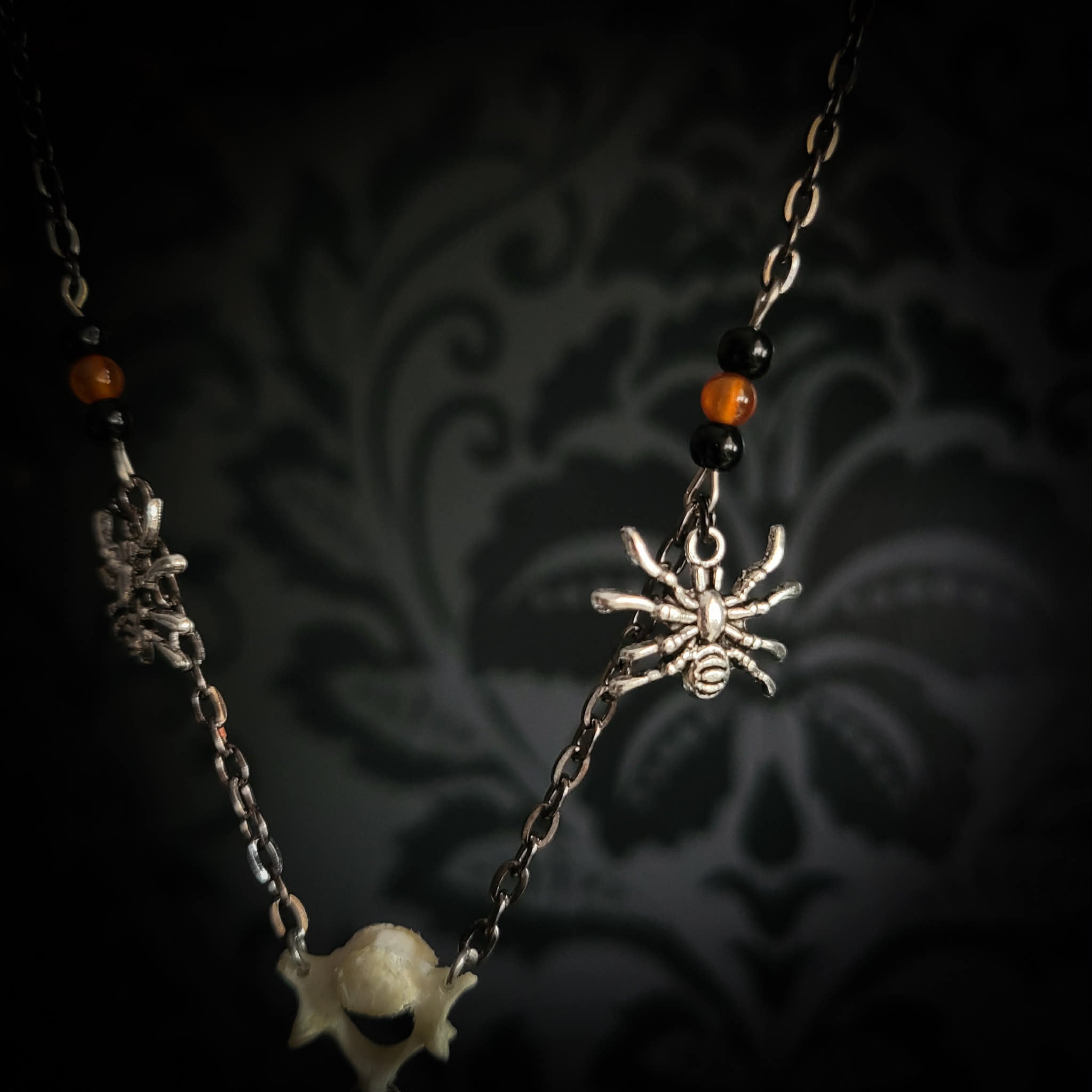 Handmade gothic necklace — tiger's eye stone and mouse jaw in resin pendant, snake skin background, vertebrae connector, metal spiders, carnelian beads