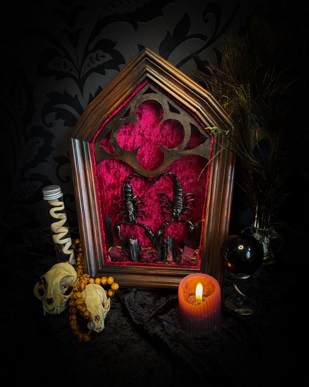 Veneficium gothic shadowbox — two preserved black scorpions arranged in a heart shape on deep crimson velvet, with hand-carved gothic tracery, preserved roses and vampire candles, in a hand-carved wooden frame with glass front. Morbid oddities.