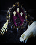 Decorative frame with skull designs and a snake on a dark background Handmade gothic wall frame featuring three real mouse skulls and a snake ornament, set against a dark velvet background. Ornate gothic frame, minimalist symmetrical composition with a dark ritual-inspired aesthetic. One-of-a-kind handcrafted piece, 12x10cm | Morbid Oddities