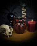Decorative setup with a skull, heart-shaped container, and lit candle on a dark background handmade gothic anatomical heart vessel hand-painted cast sculpture dark decor
