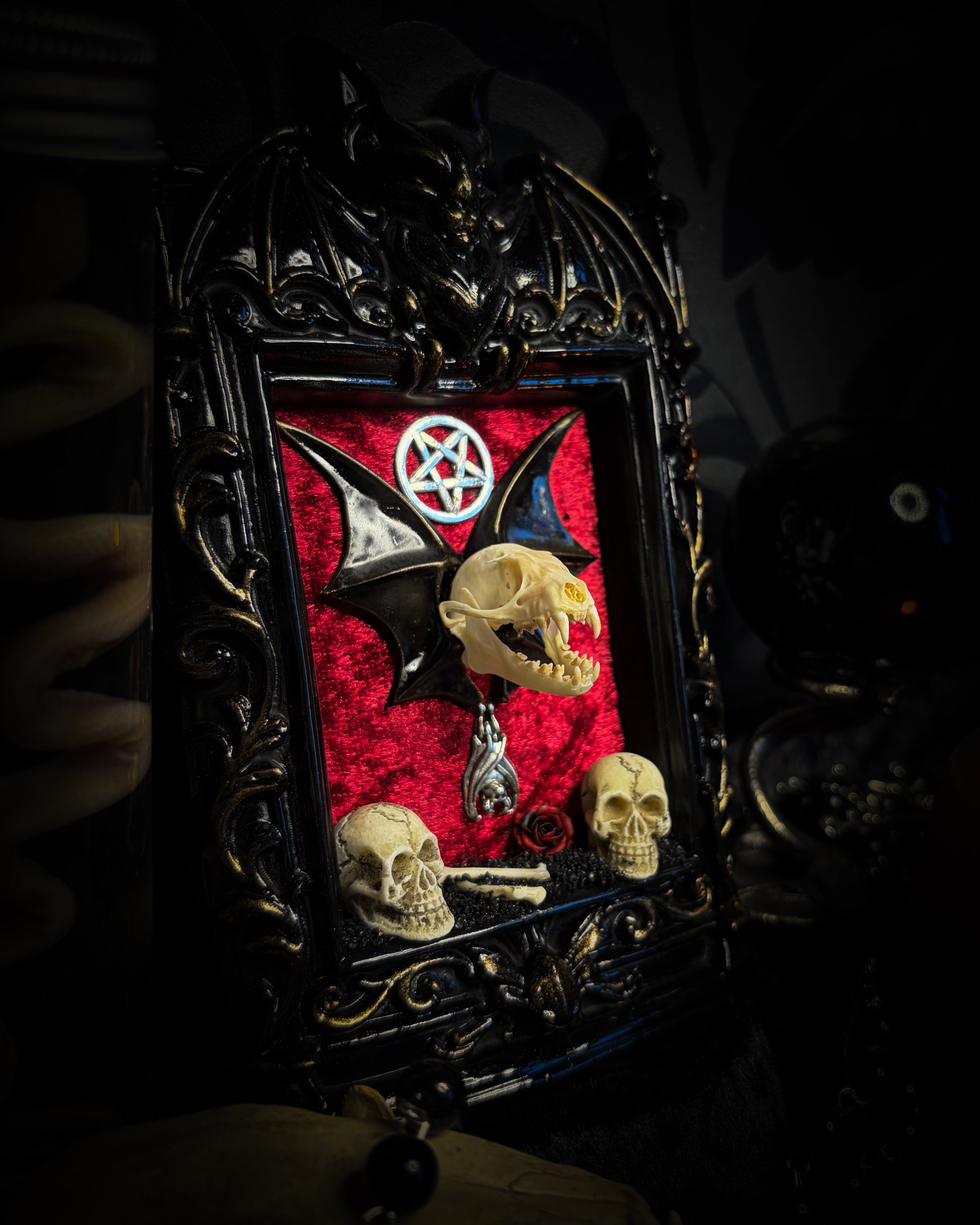 Crimson Ritual — handmade gothic wall relic, ready to ship. Real bat skull with hand-cast wings on crimson crushed velvet in black and gold frame with sculpted bat, ornamental skulls, wax rose and pentagram details. One-of-a-kind dark decor, 16x11cm.