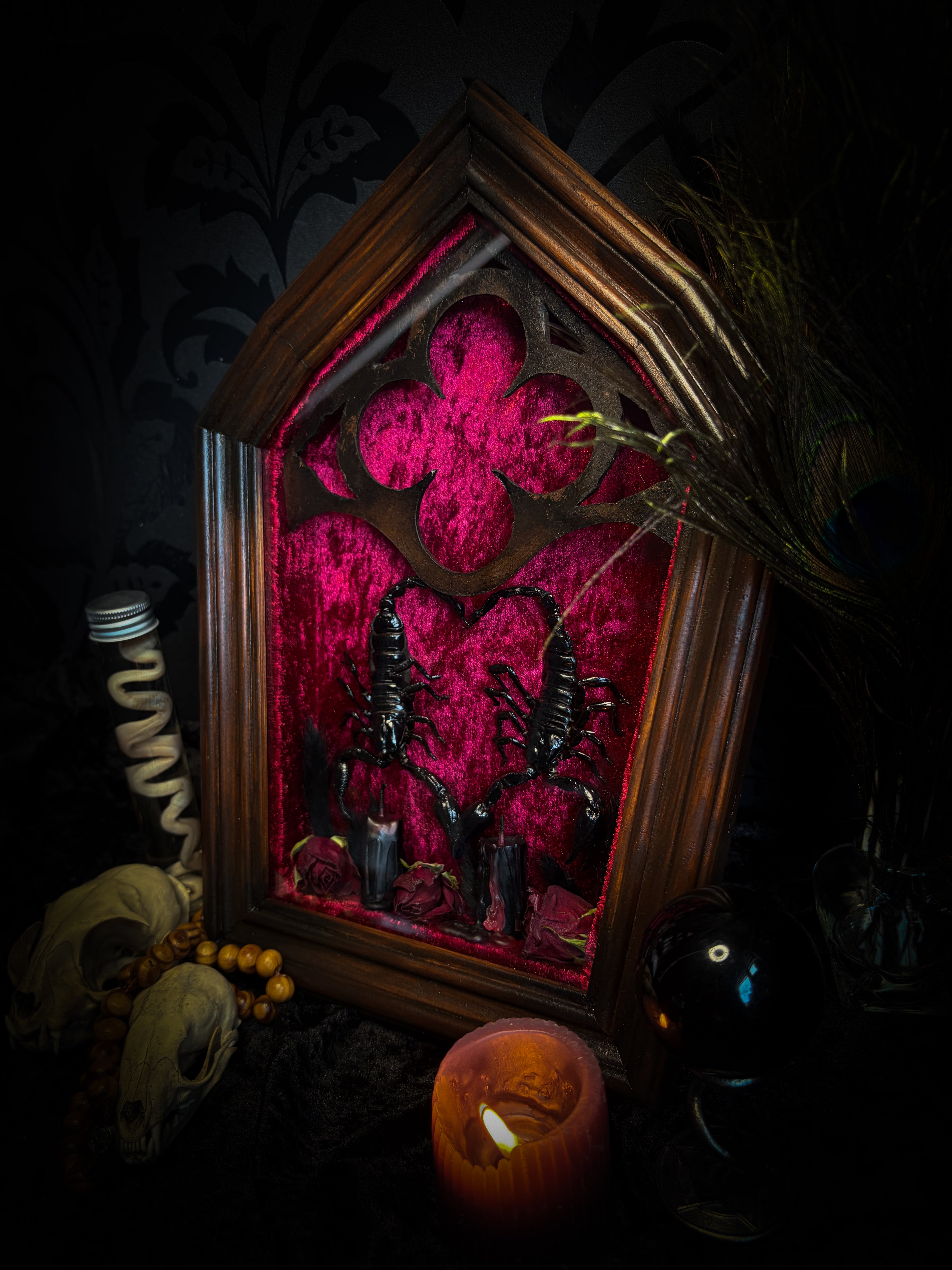 Veneficium gothic shadowbox — two preserved black scorpions arranged in a heart shape on deep crimson velvet, with hand-carved gothic tracery, preserved roses and vampire candles, in a hand-carved wooden frame with glass front. Morbid oddities.