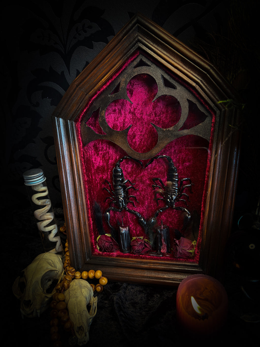 Veneficium gothic shadowbox — two preserved black scorpions arranged in a heart shape on deep crimson velvet, with hand-carved gothic tracery, preserved roses and vampire candles, in a hand-carved wooden frame with glass front. Morbid oddities.