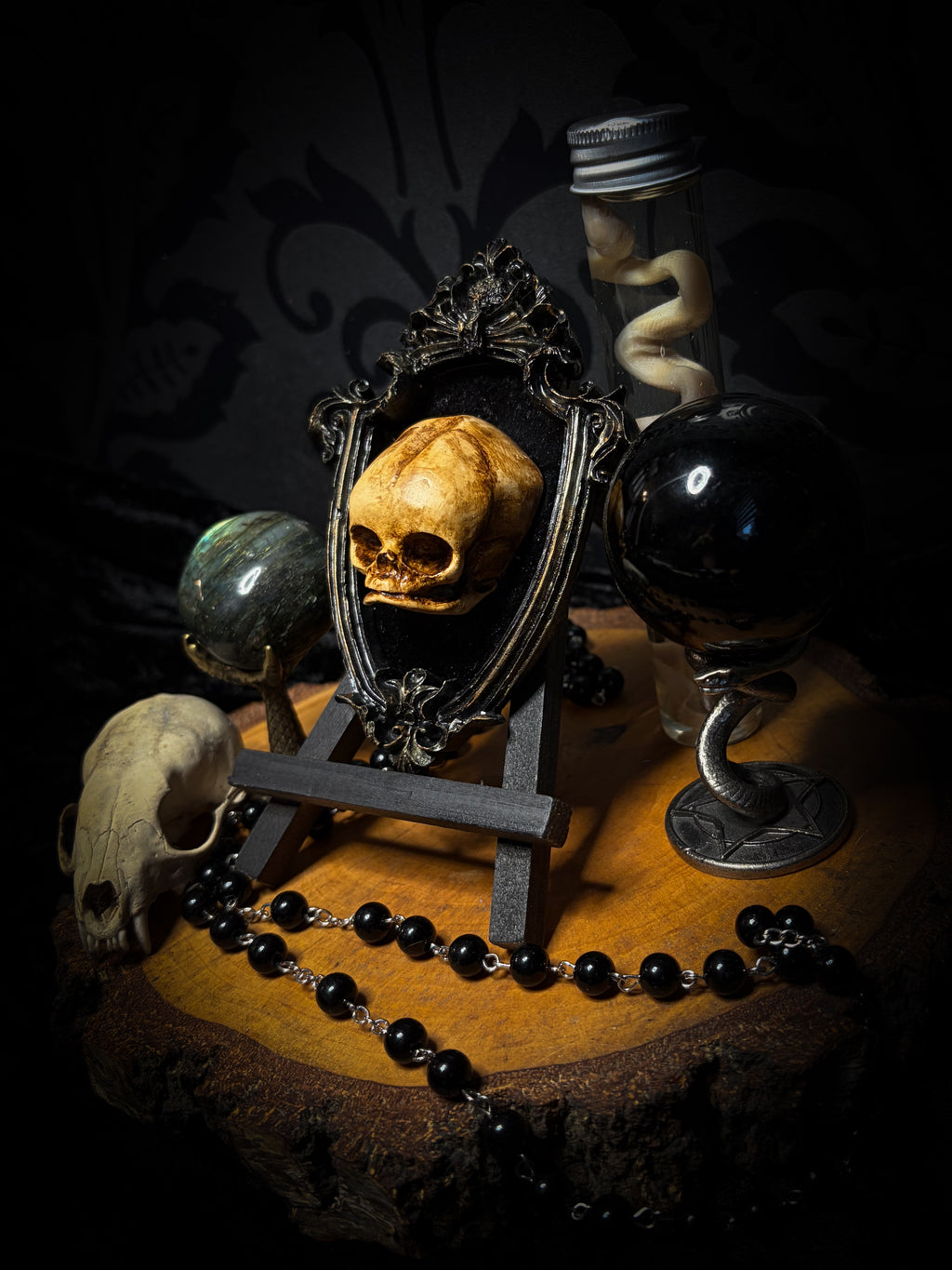 Little Vigil by Morbid Oddities, a patinated skull cast on black velvet in an ornate dark shield-shaped frame with aged metallic detailing.⠋

