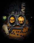 Kindred Remains by Morbid Oddities, one adult and one newborn patinated skull cast on black velvet in an ornate black double frame with metallic detailing.