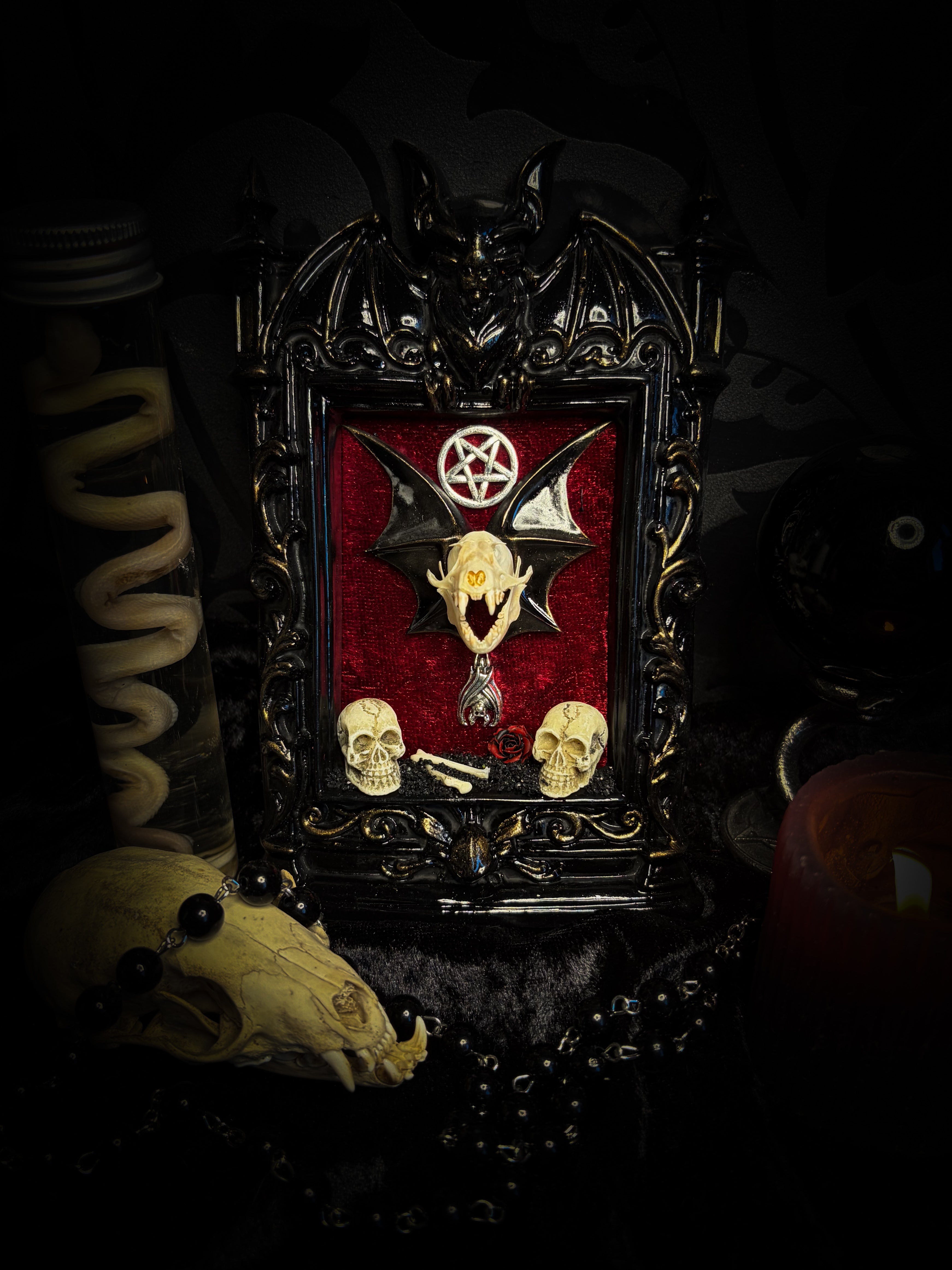 Crimson Ritual — handmade gothic wall relic, ready to ship. Real bat skull with hand-cast wings on crimson crushed velvet in black and gold frame with sculpted bat, ornamental skulls, wax rose and pentagram details. One-of-a-kind dark decor, 16x11cm.