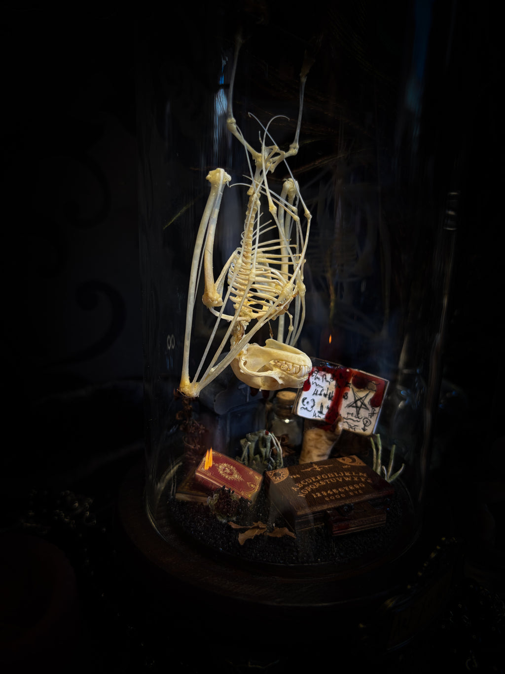 Handmade gothic occult display — bat skeleton in glass dome with Leviathan sigil, cemetery vignette with ouija board and necromancer book, 12x24cm