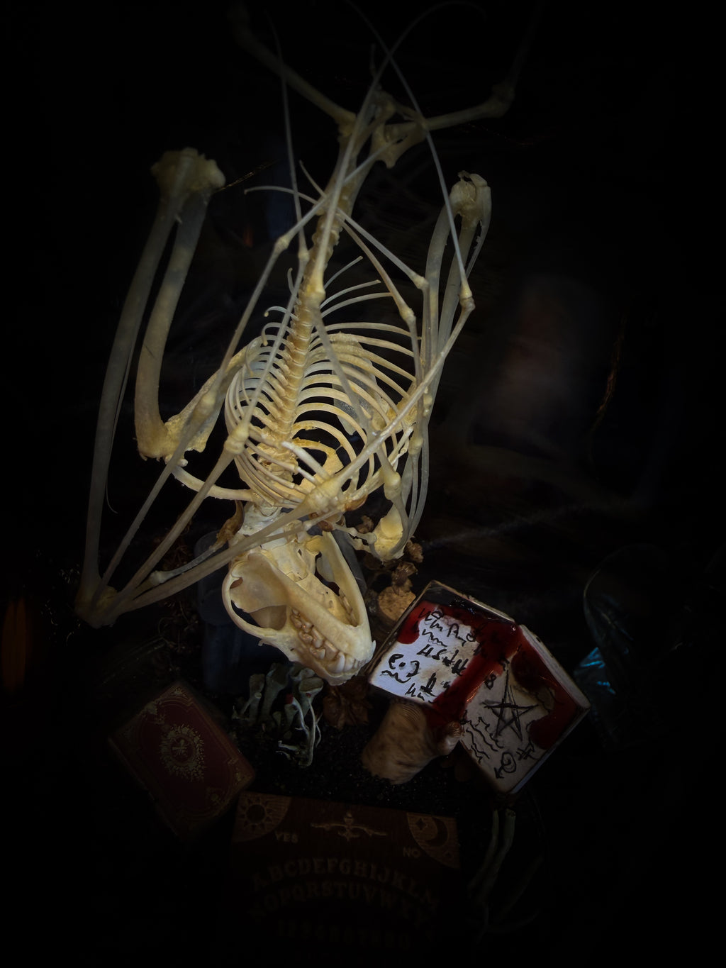 Handmade gothic occult display — bat skeleton in glass dome with Leviathan sigil, cemetery vignette with ouija board and necromancer book, 12x24cm