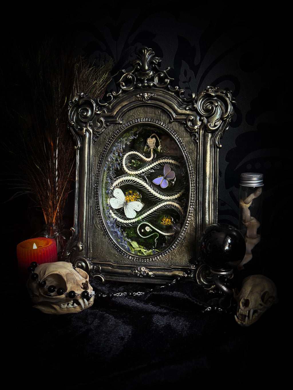 Decorative mirror with intricate design surrounded by skulls and candles on a dark background