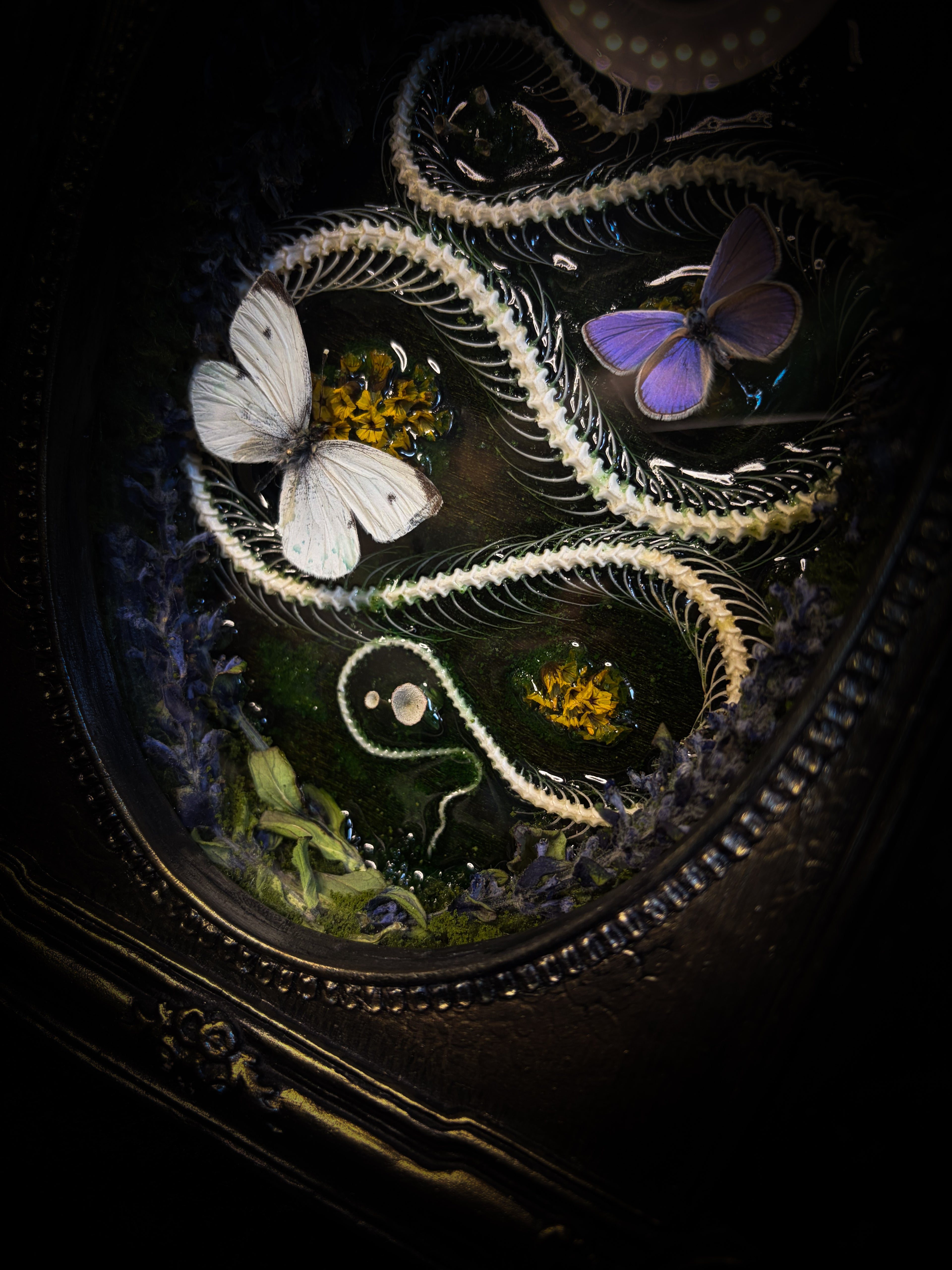 Decorative object with snake, butterfly, and floral elements on a dark background
