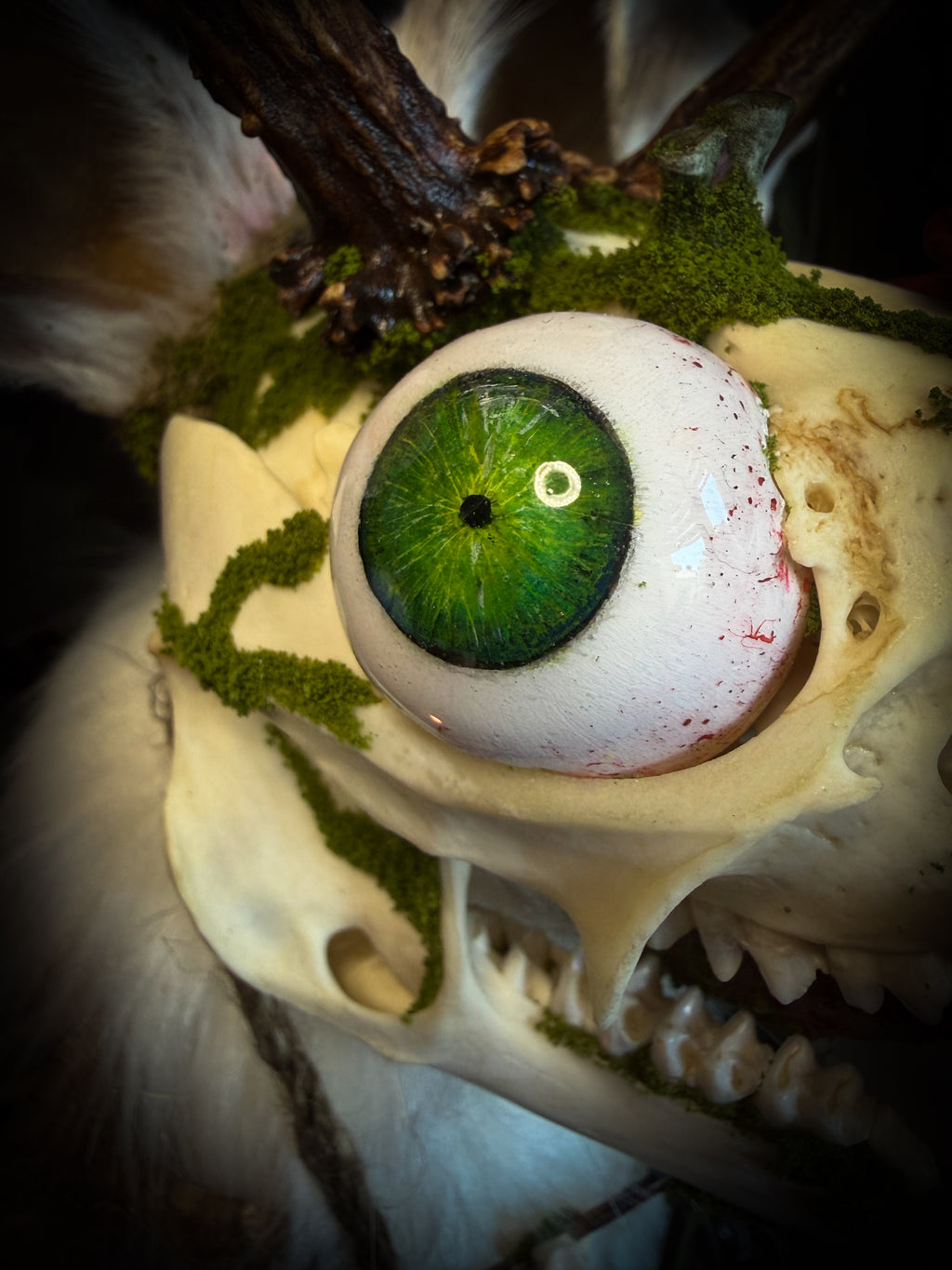Skull with a green artificial eye and moss-like material Spiritus Silvae handmade gothic art puppet — full view, suede body with roebuck horns, rabbit ears, bird talons and mushrooms on base