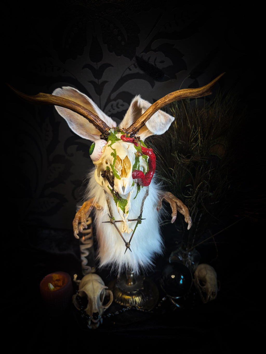 Decorative head with antlers and feathers on a dark background Spiritus Silvae handmade gothic art puppet — full view, suede body with roebuck horns, rabbit ears, bird talons and mushrooms on base