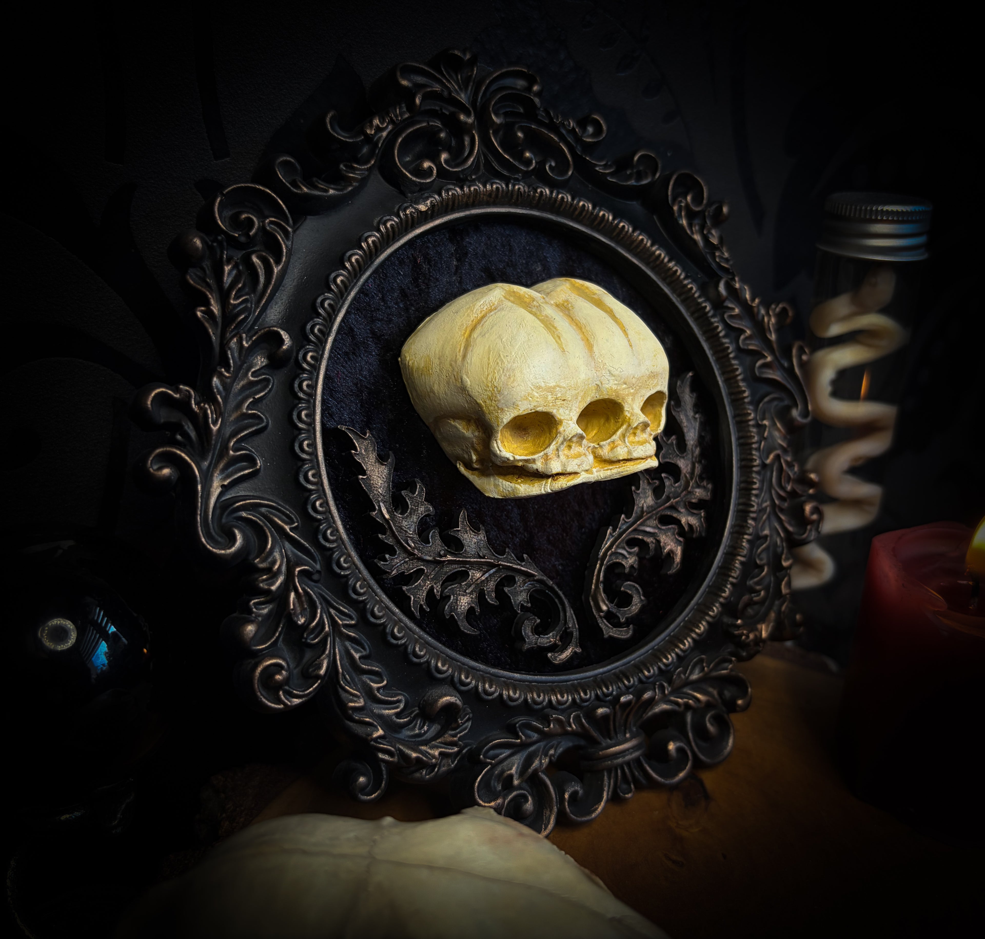 Decorative skull sculpture in an ornate frame on a dark background