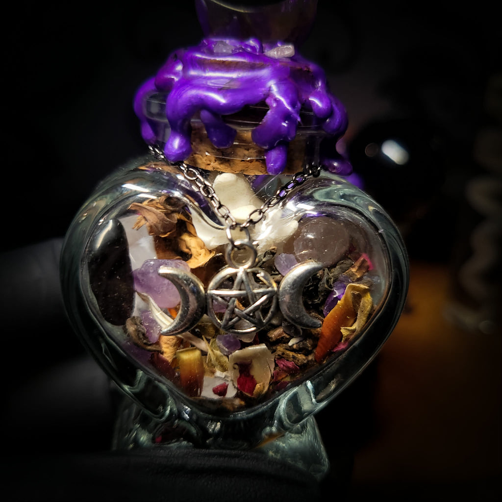 Handmade gothic twin spell jar set — two heart-shaped glass vessels sealed with violet wax and amethyst moon, filled with herbs, crystals and bones for love binding ritual