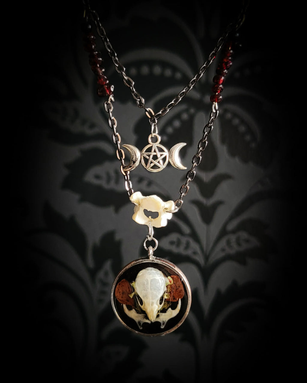 Handmade gothic necklace — real mouse skull in circular resin pendant, dried red petals, triple moon pentagram charm, garnet beads