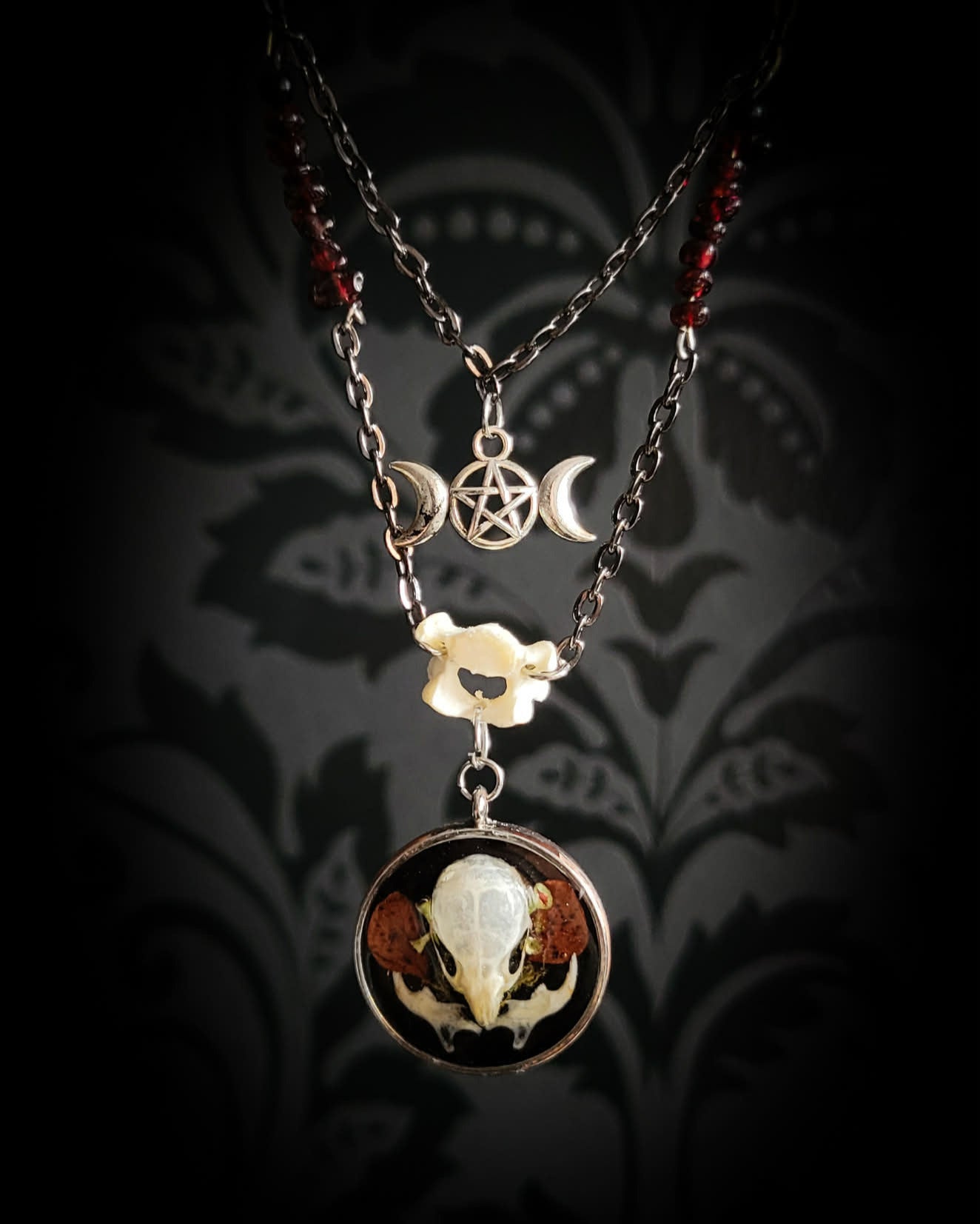 Handmade gothic necklace — real mouse skull in circular resin pendant, dried red petals, triple moon pentagram charm, garnet beads