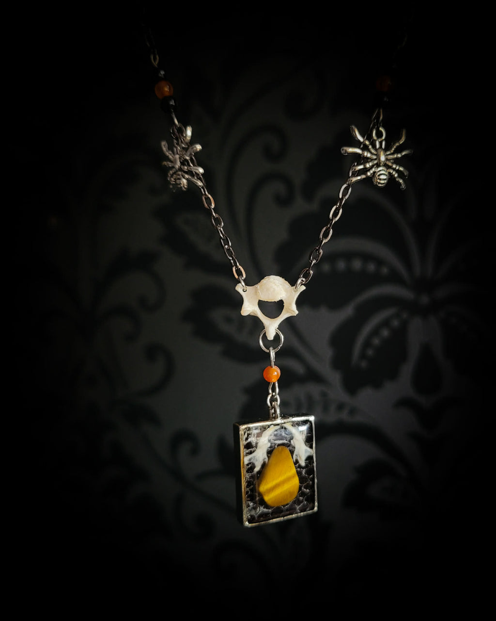 Handmade gothic necklace — tiger's eye stone and mouse jaw in resin pendant, snake skin background, vertebrae connector, metal spiders, carnelian beads